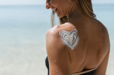 Femme souriant avec de la crème solaire sur les épaules