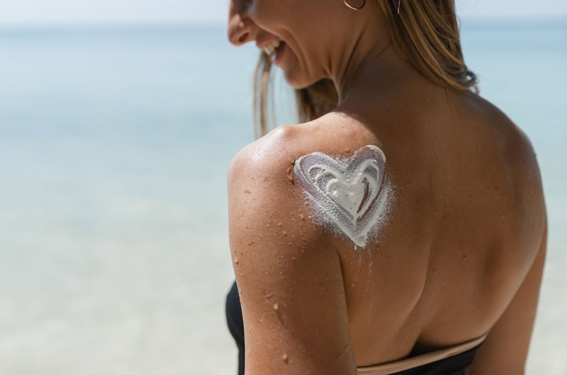 Femme souriant avec de la crème solaire sur les épaules